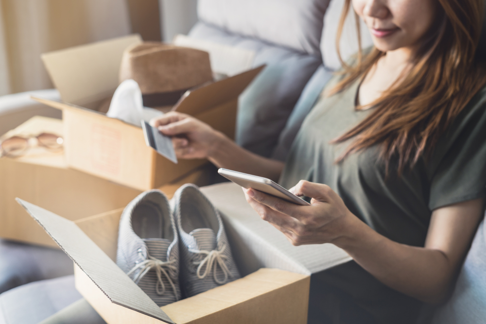 ung kvinna fick online shopping paket öppna lådor och köpa mode objekt med hjälp av kreditkort